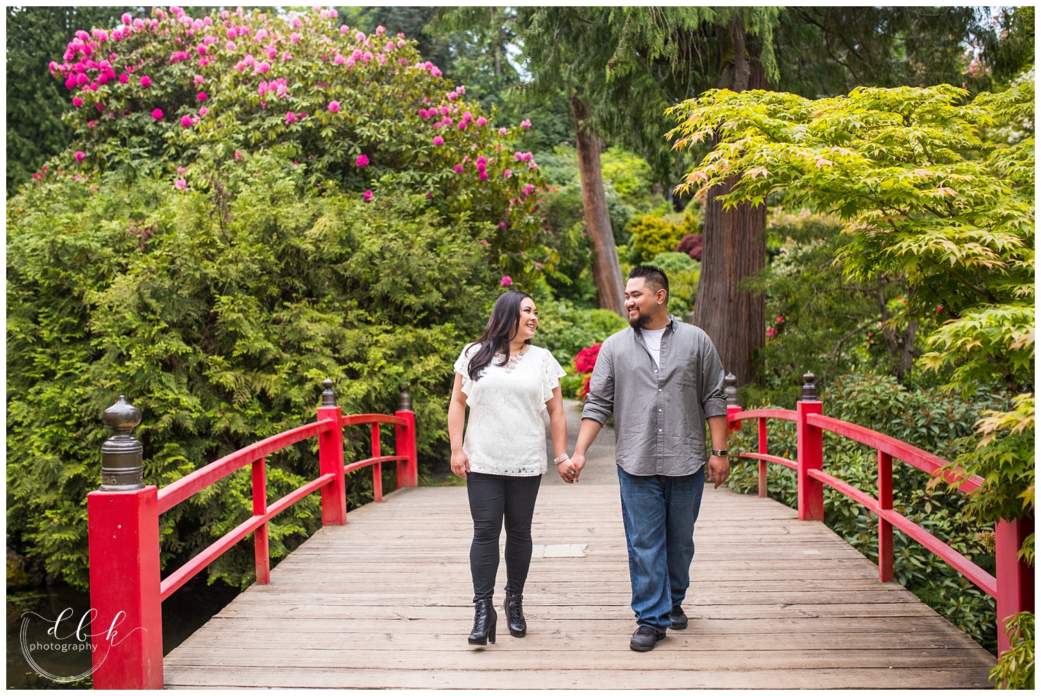 couple walking on red bridge in Japanese garden at Kubota Garden in Seattle