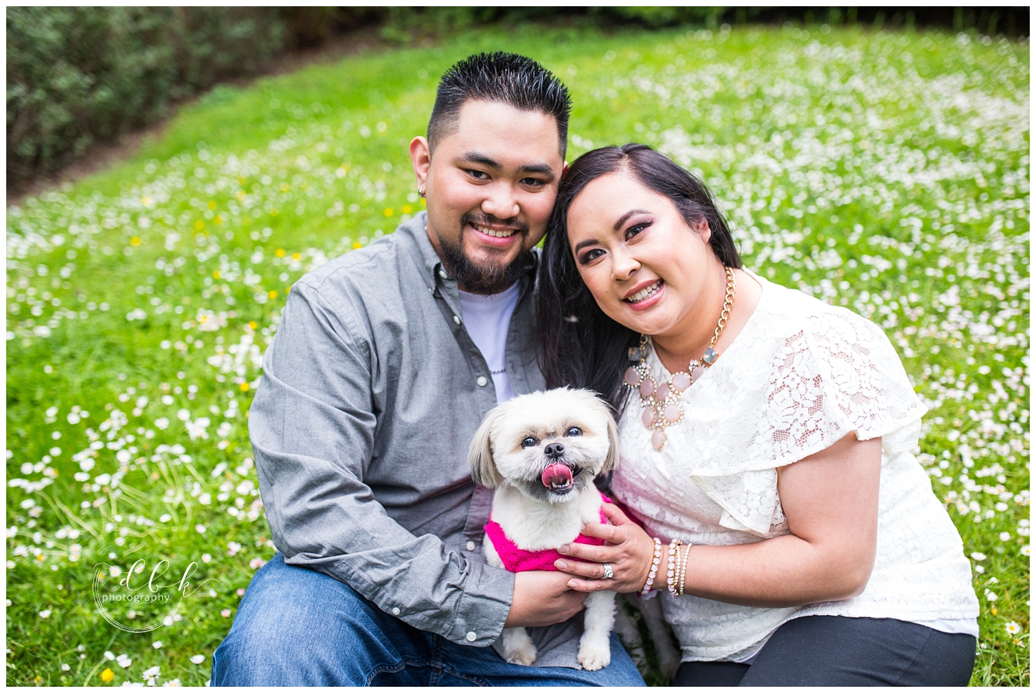 couple sitting in grass with puppy for spring engagement pictures at Kubota Garden