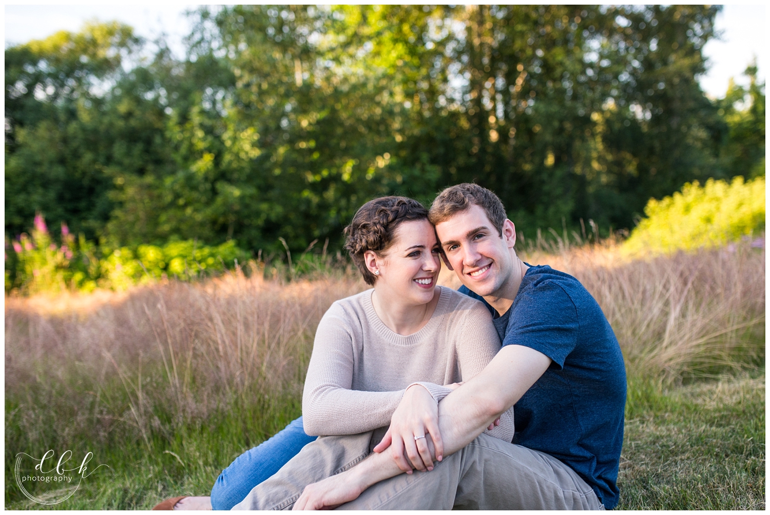 couple wearing blue and pink sitting among tall grass for engagement pictures at Juanita Bay Park