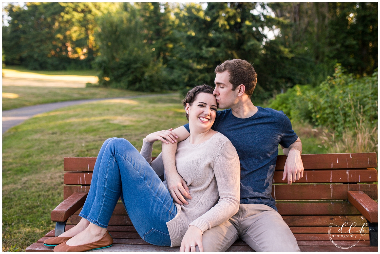 cute couple sitting on a bench for engagement pictures at Juanita Bay Park in Kirkland, Washington