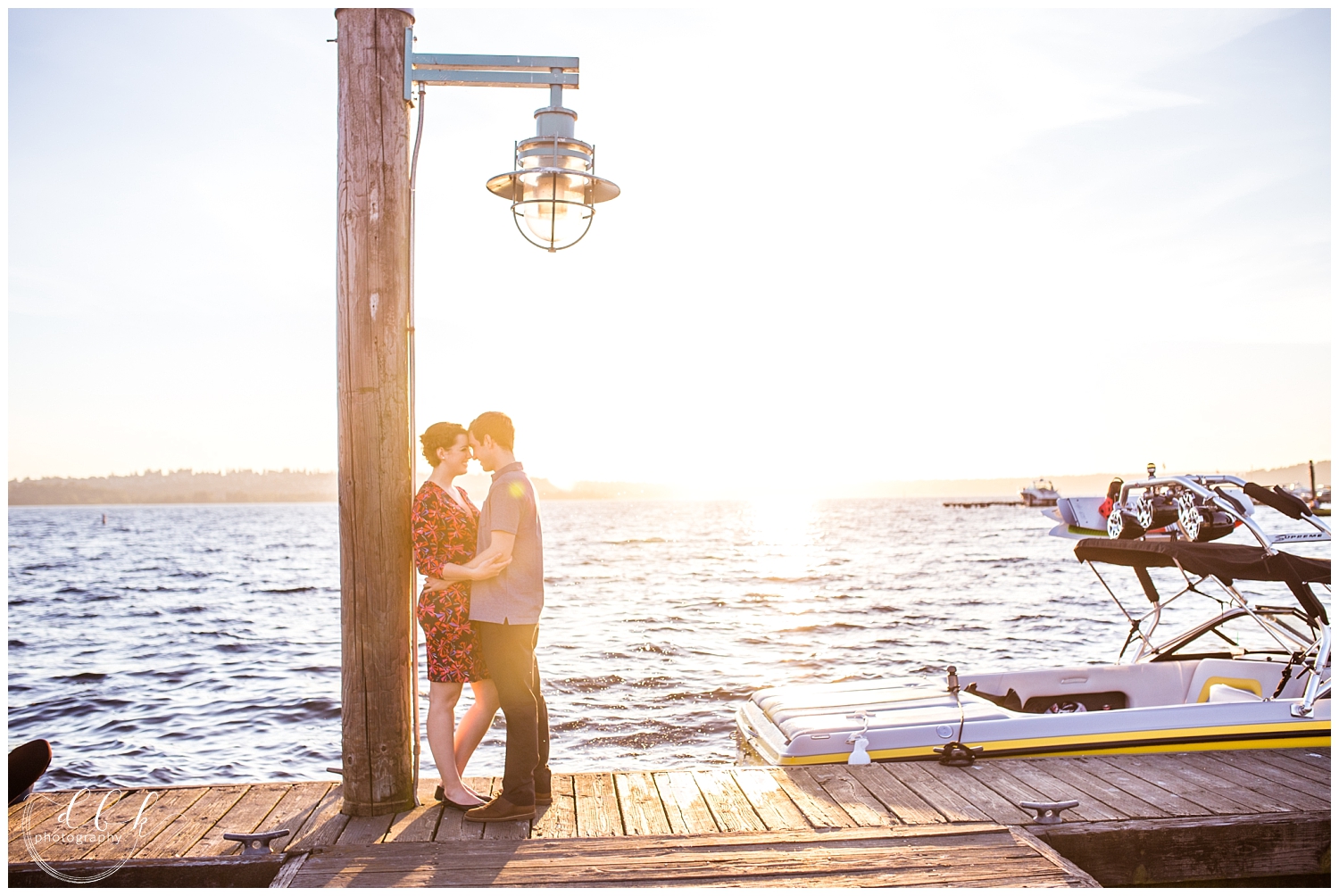 couple standing under a lamp post as the sun sets over the Kirkland Marina