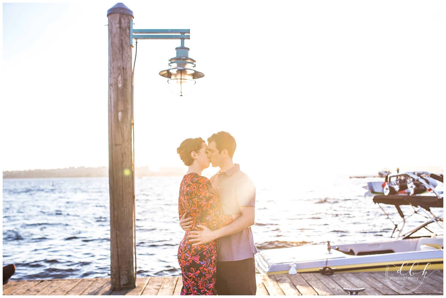 couple kissing by the water as the sun sets over the Kirkland Marina