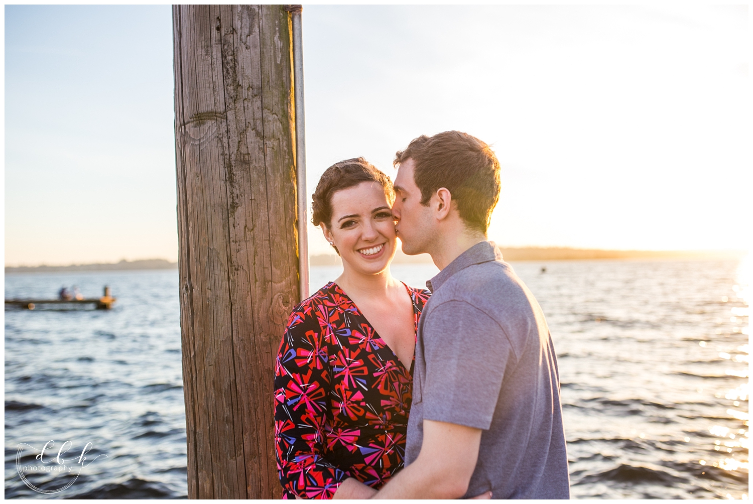 future groom gives his future bride a kiss on the cheek for engagement pictures at Kirkland Marina
