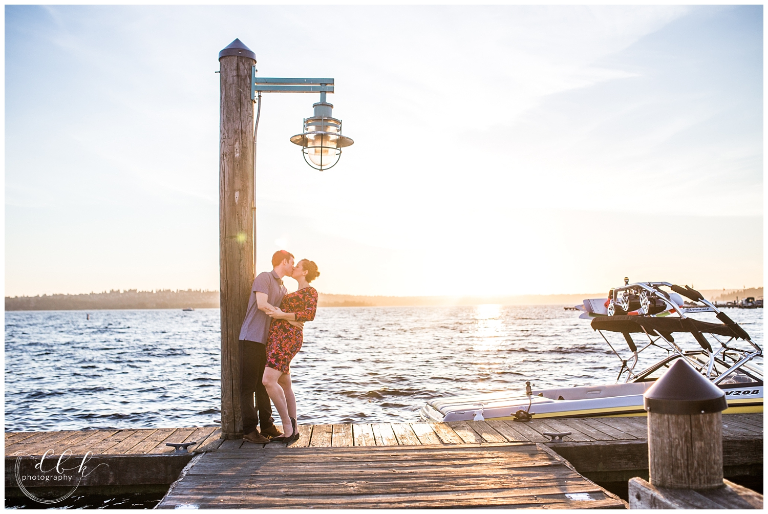 couple kissing under a lamp post as the sun sets over the Kirkland Marina