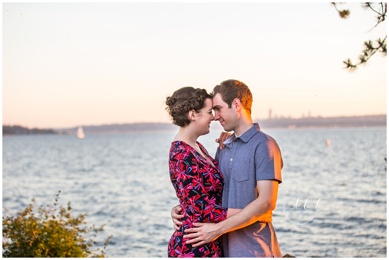 couple stands with foreheads touching in front of Kirkland Marina at sunset