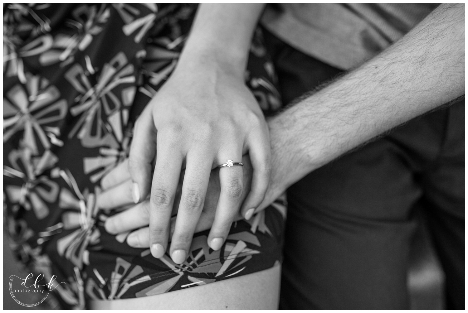 black and white picture of couple holding hands, featuring engagement ring