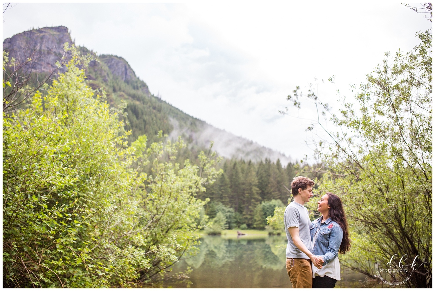 couple faces each other in front of foggy mountain backdrop