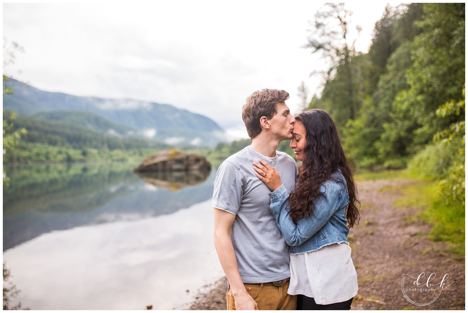 man kissing his fiance's forehead by the lake in North Bend