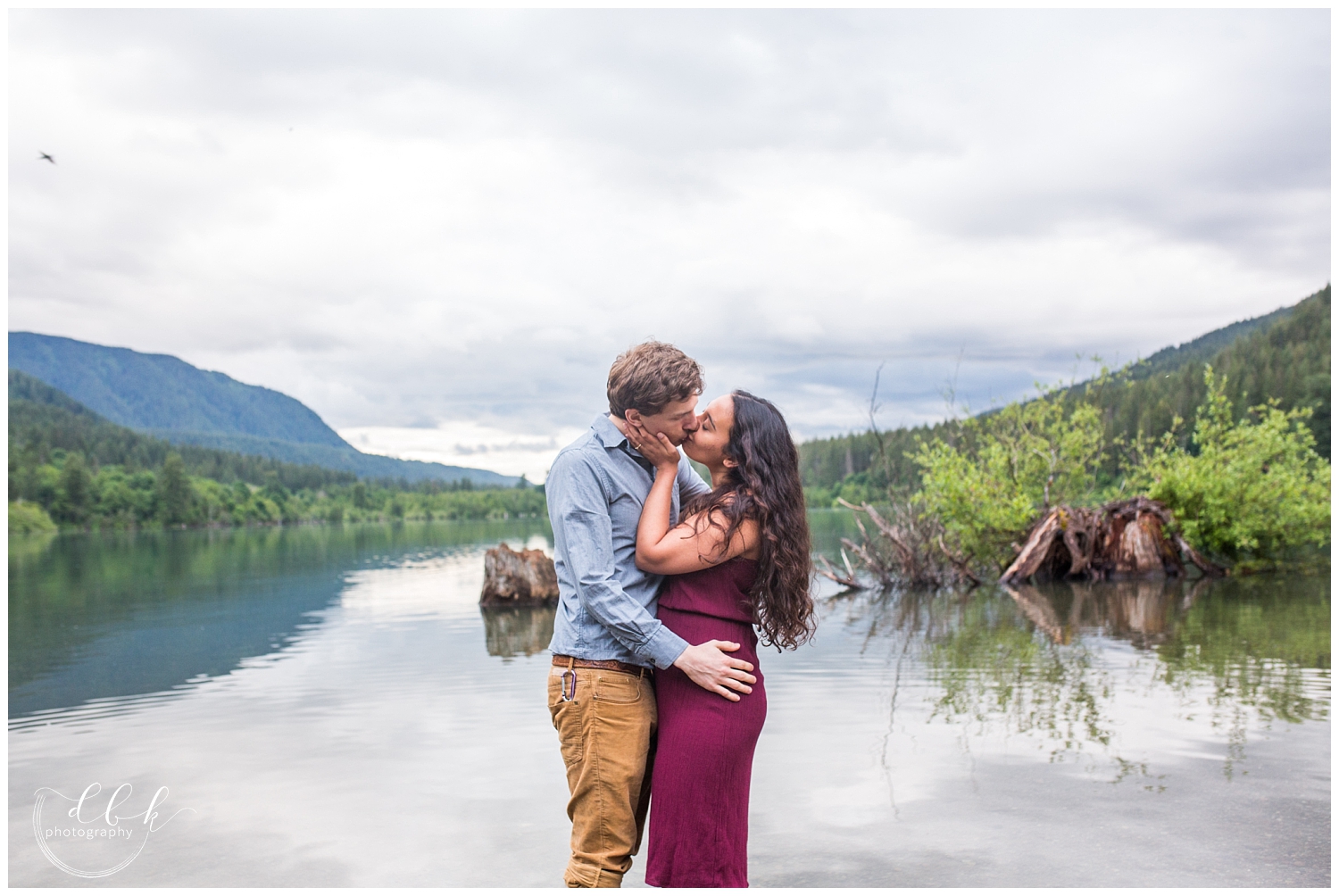 kissing couple standing in a lake in the Snoqualmie forest