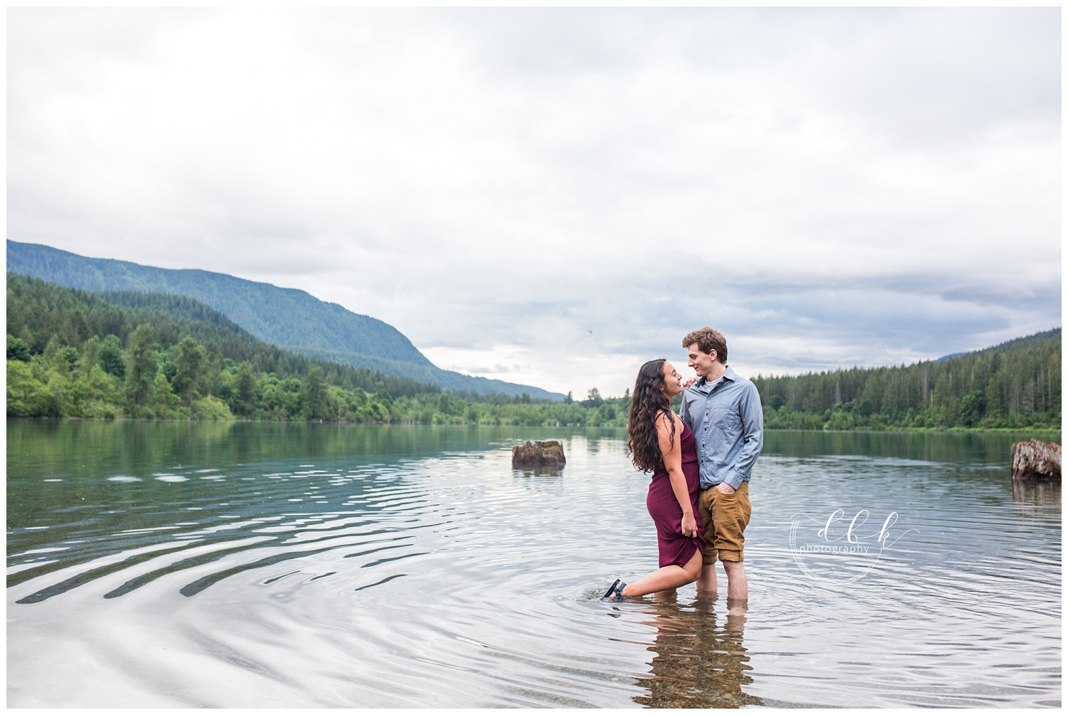 cute couple standing in the water in front of Cascade Mountain backdrop
