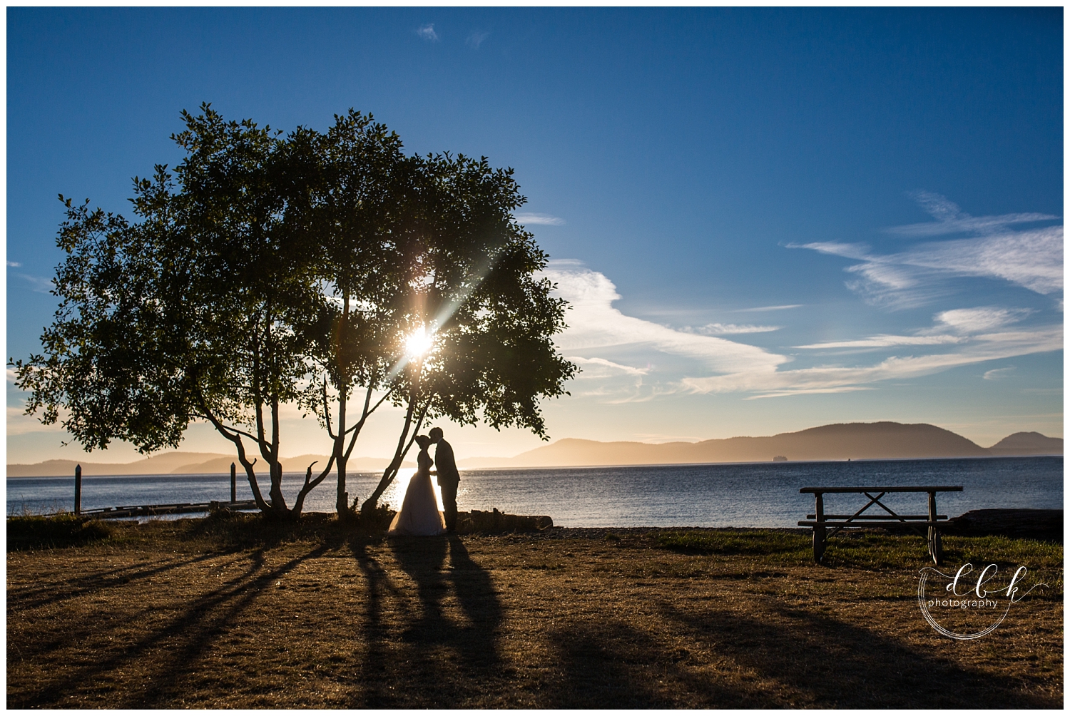 silhouette image of bride and groom kissing in front of ocean backdrop at Washington Park in Anacortes