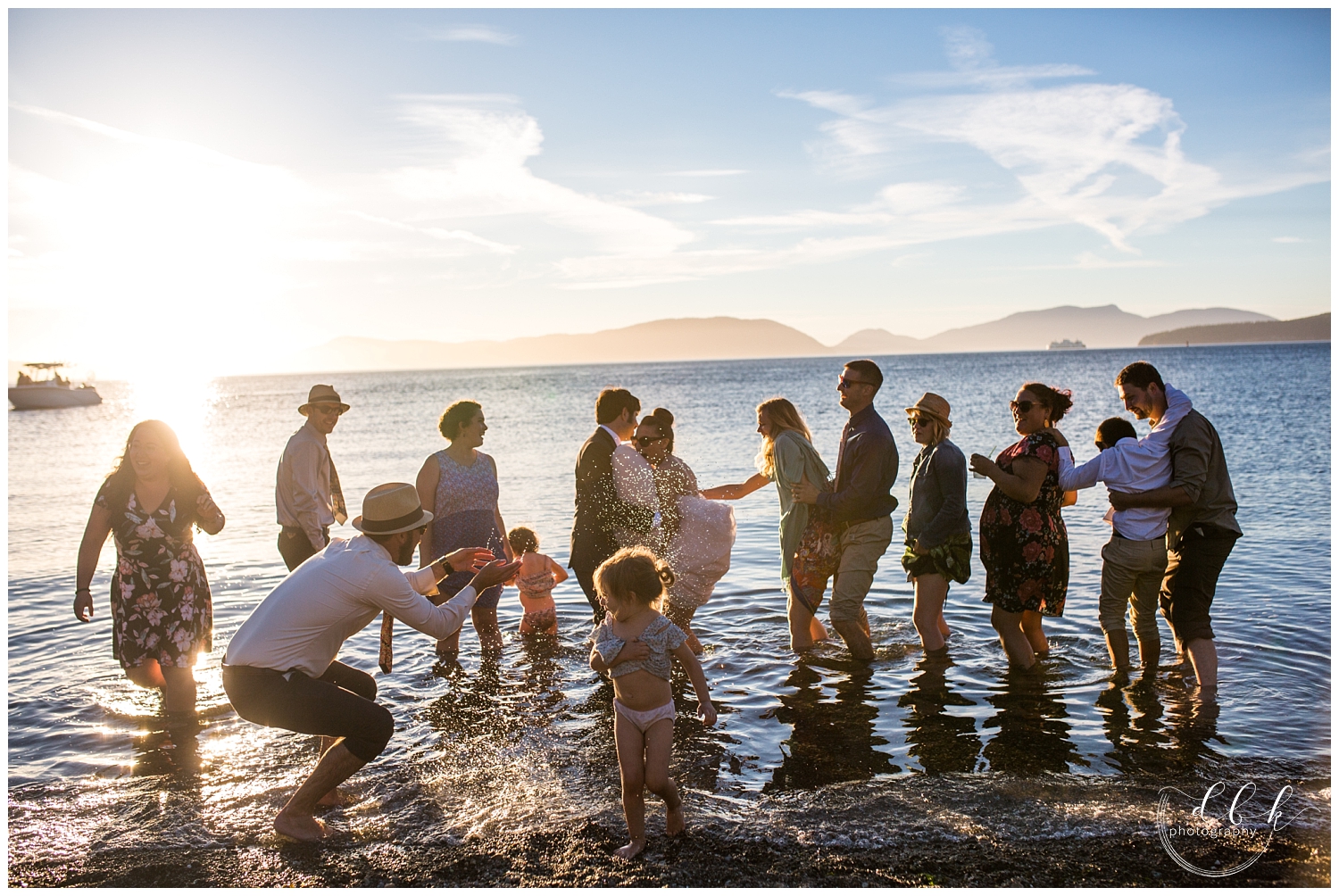 bridal party splashing in the water of the Puget Sound together at sunset at Anacortes wedding in Washington Park