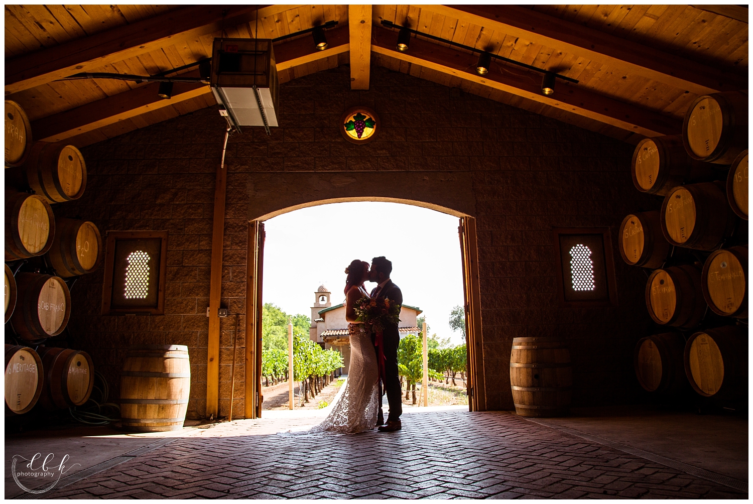 bride and groom silhouetted against winery backdrop