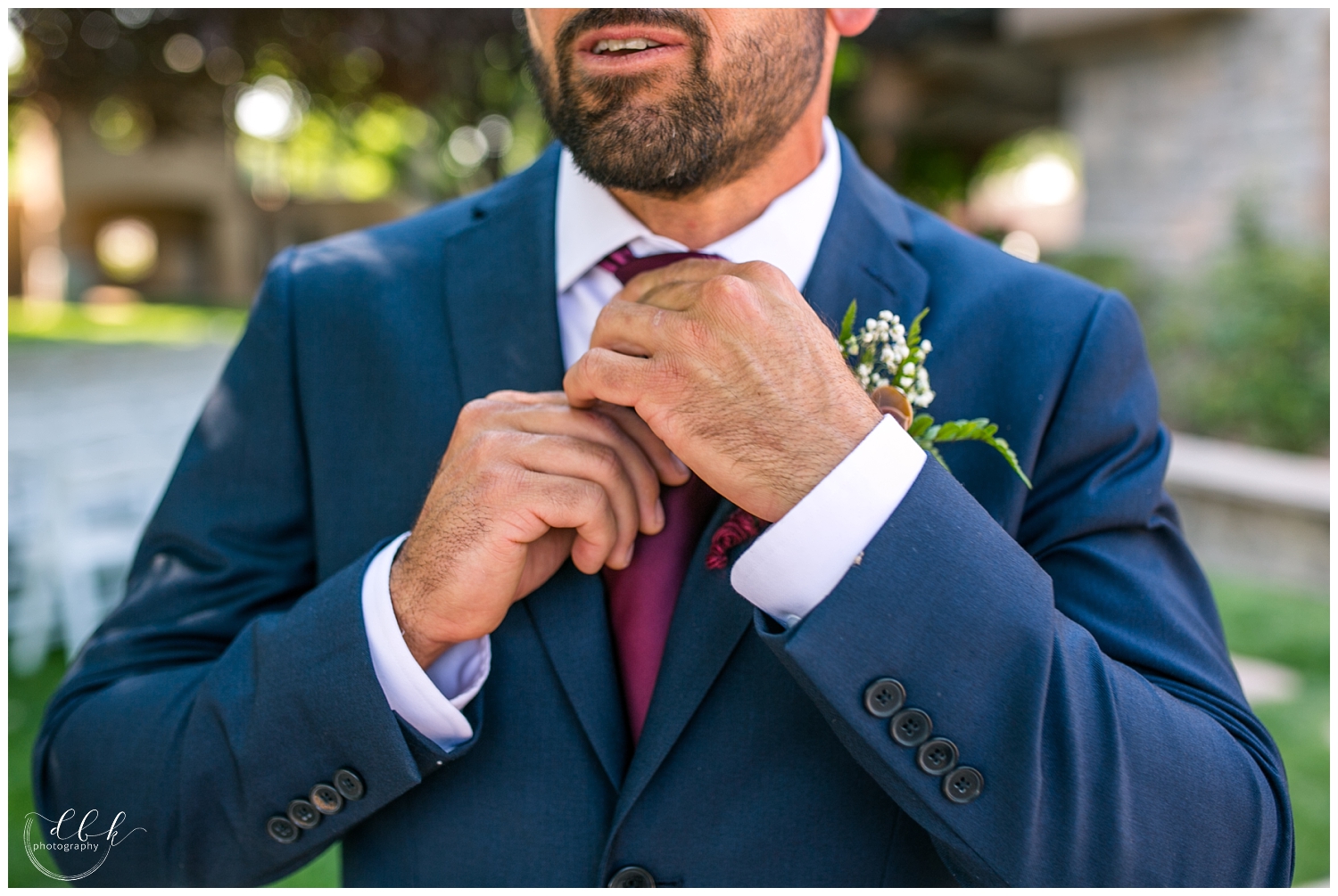 groom adjusting his maroon tie