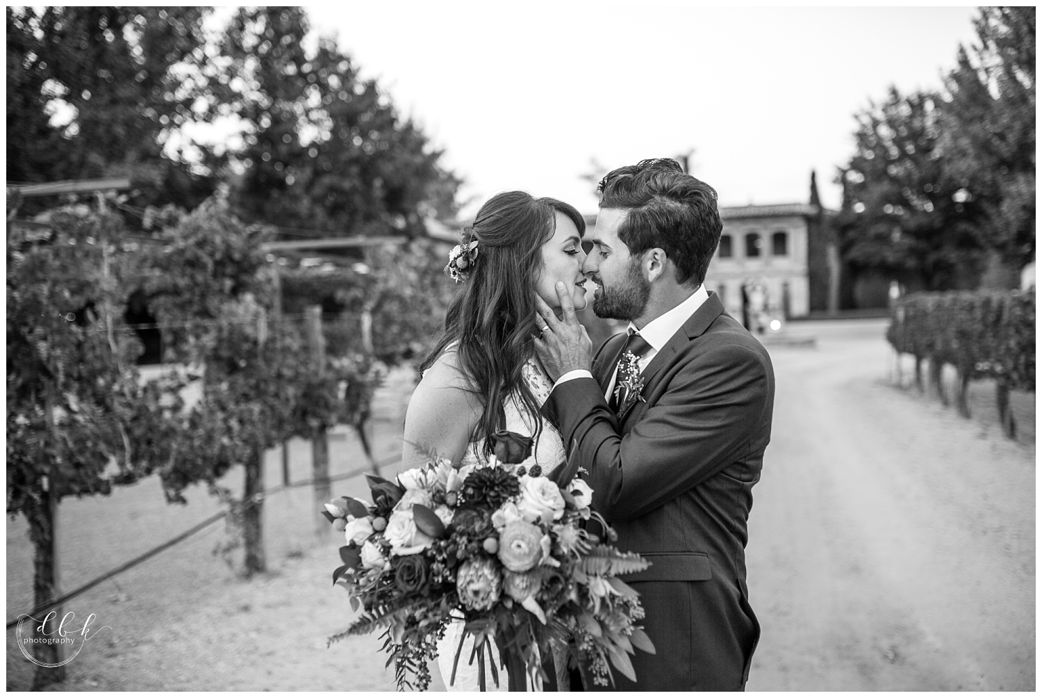 groom pulling bride in for a kiss in driveway at Casa Rondena Winery black and white portrait