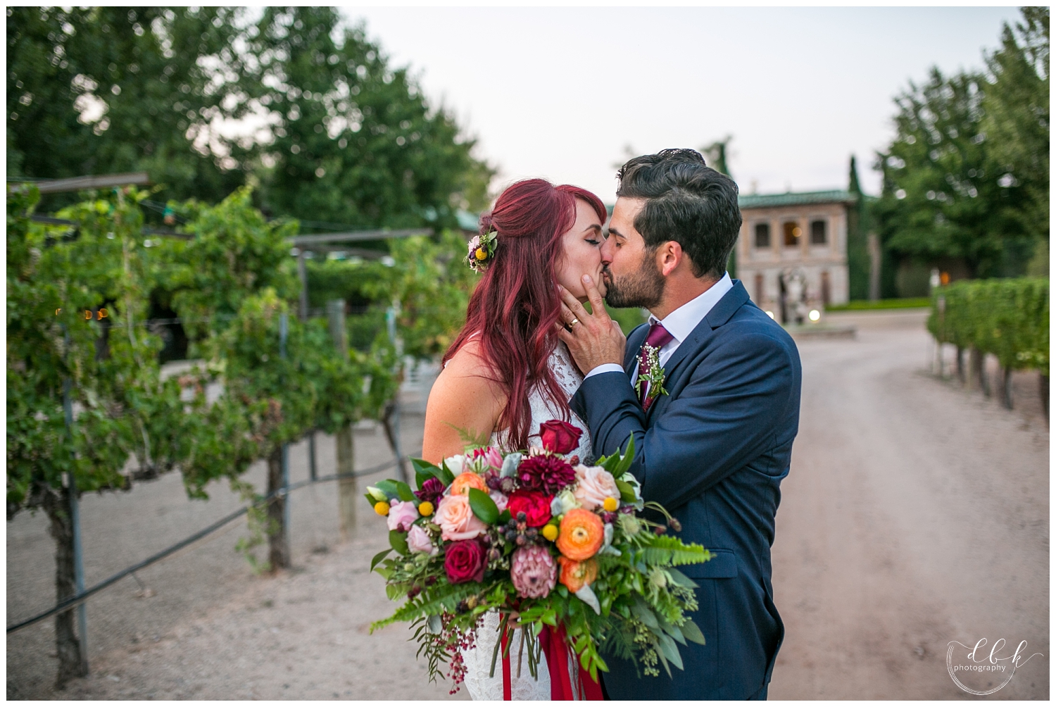 groom kissing bride with his hand on her cheek in driveway at Casa Rondena Winery