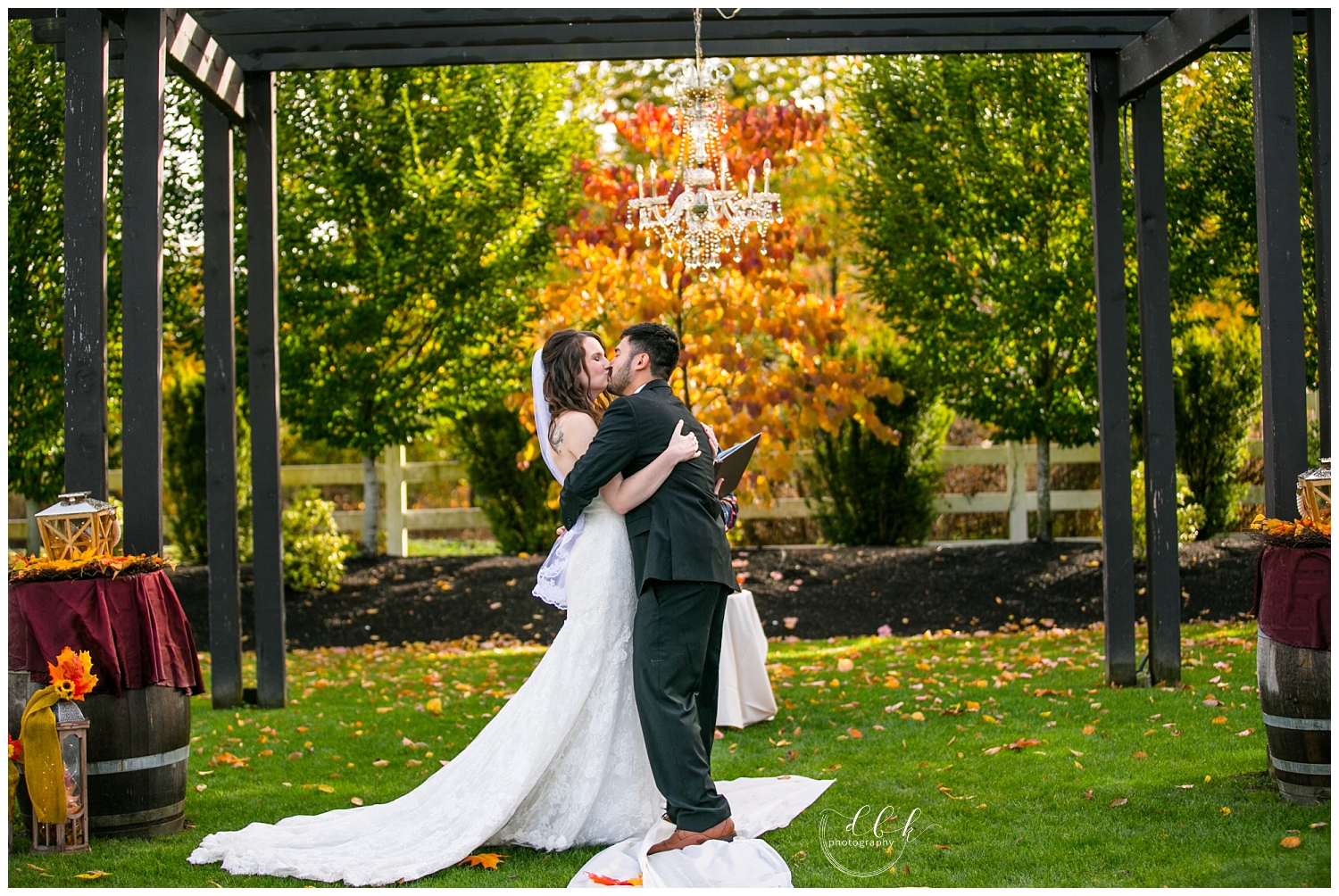 bride and groom's first kiss at fall wedding ceremony at Filigree Farm in Buckley, Washington