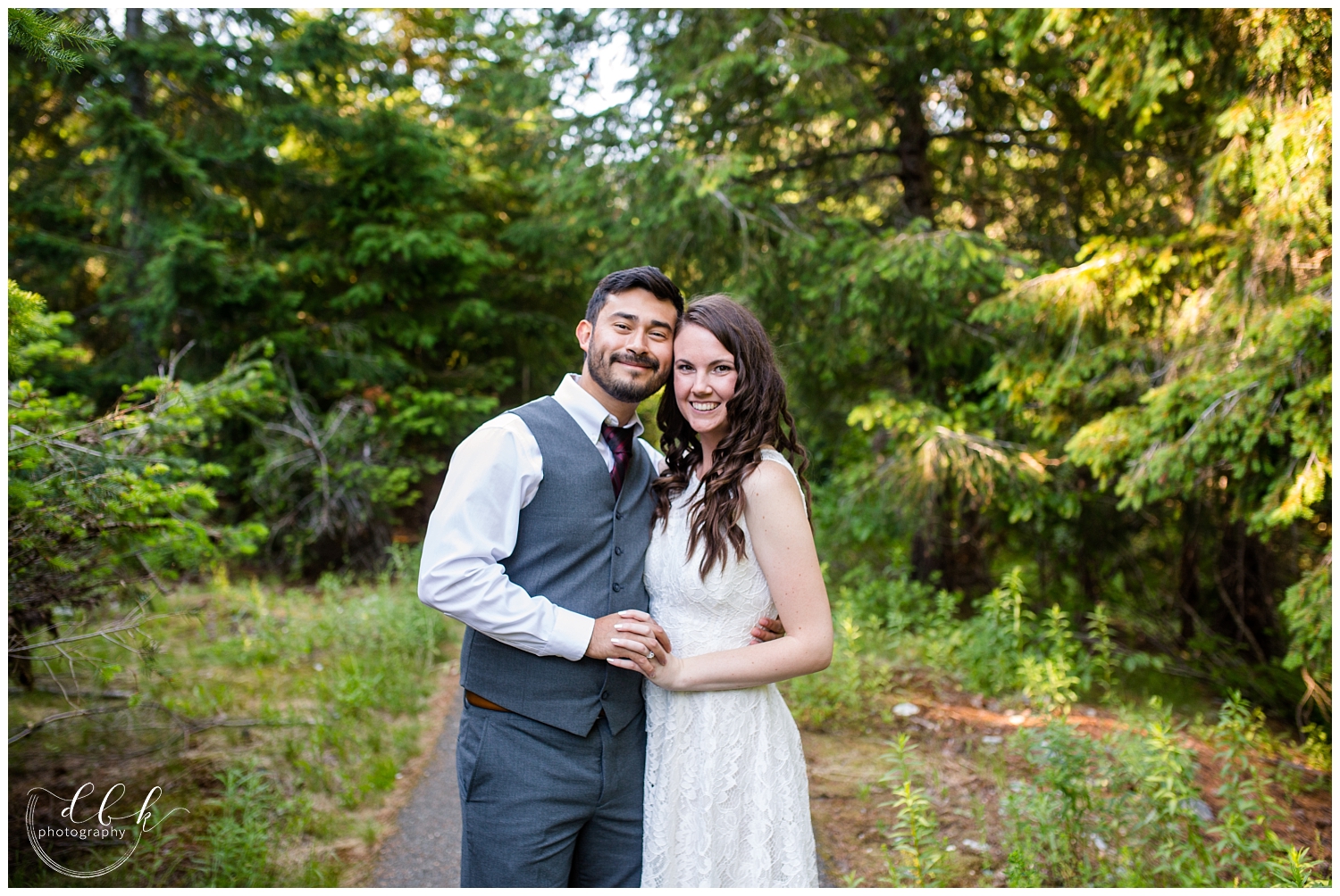 wedding couple wearing white dress and gray suit with purple tie looking at the camera for Gold Creek Pond engagement portraits