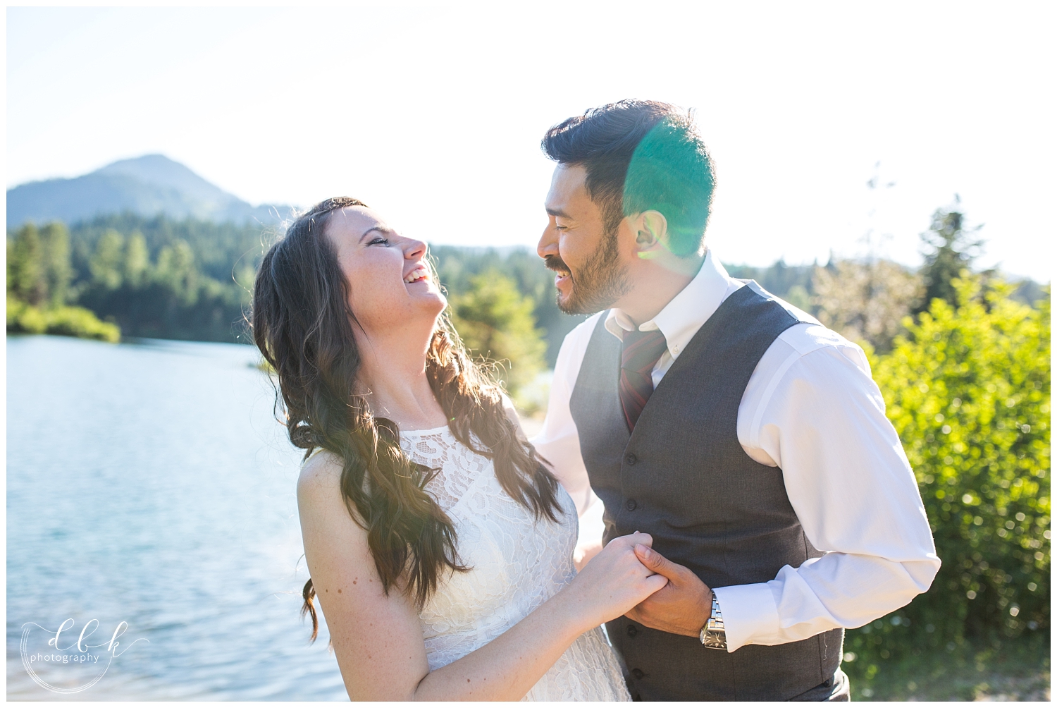 wedding couple laughing together on the water at Gold Creek Pond during summer engagement pictures