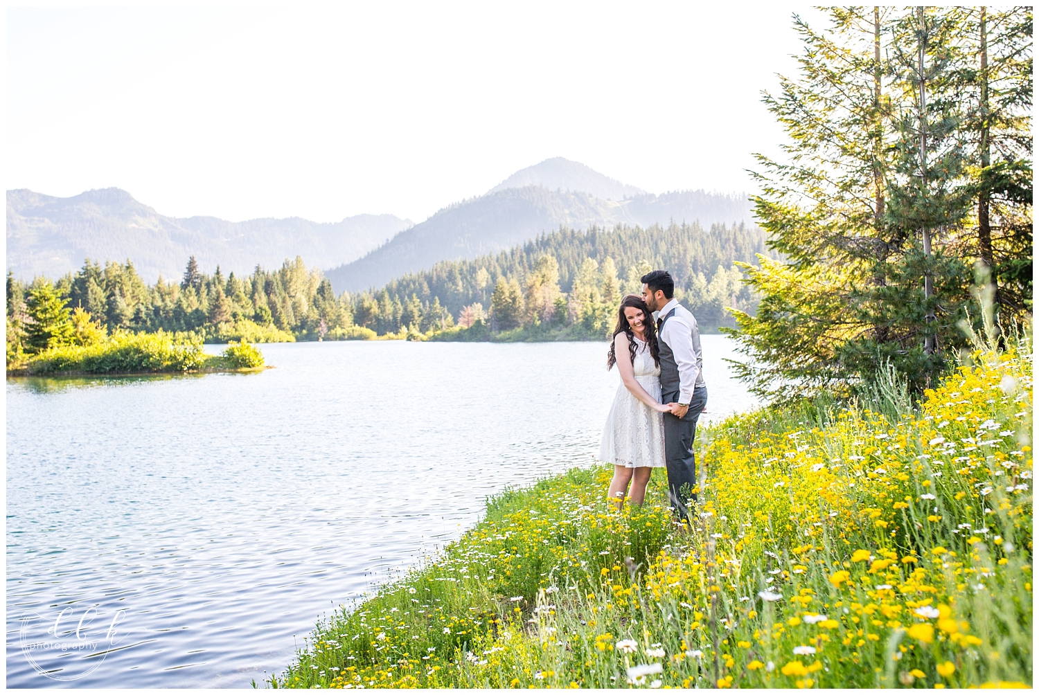 groom kissing his bride's head in field of wildflowers at Gold Creek Pond
