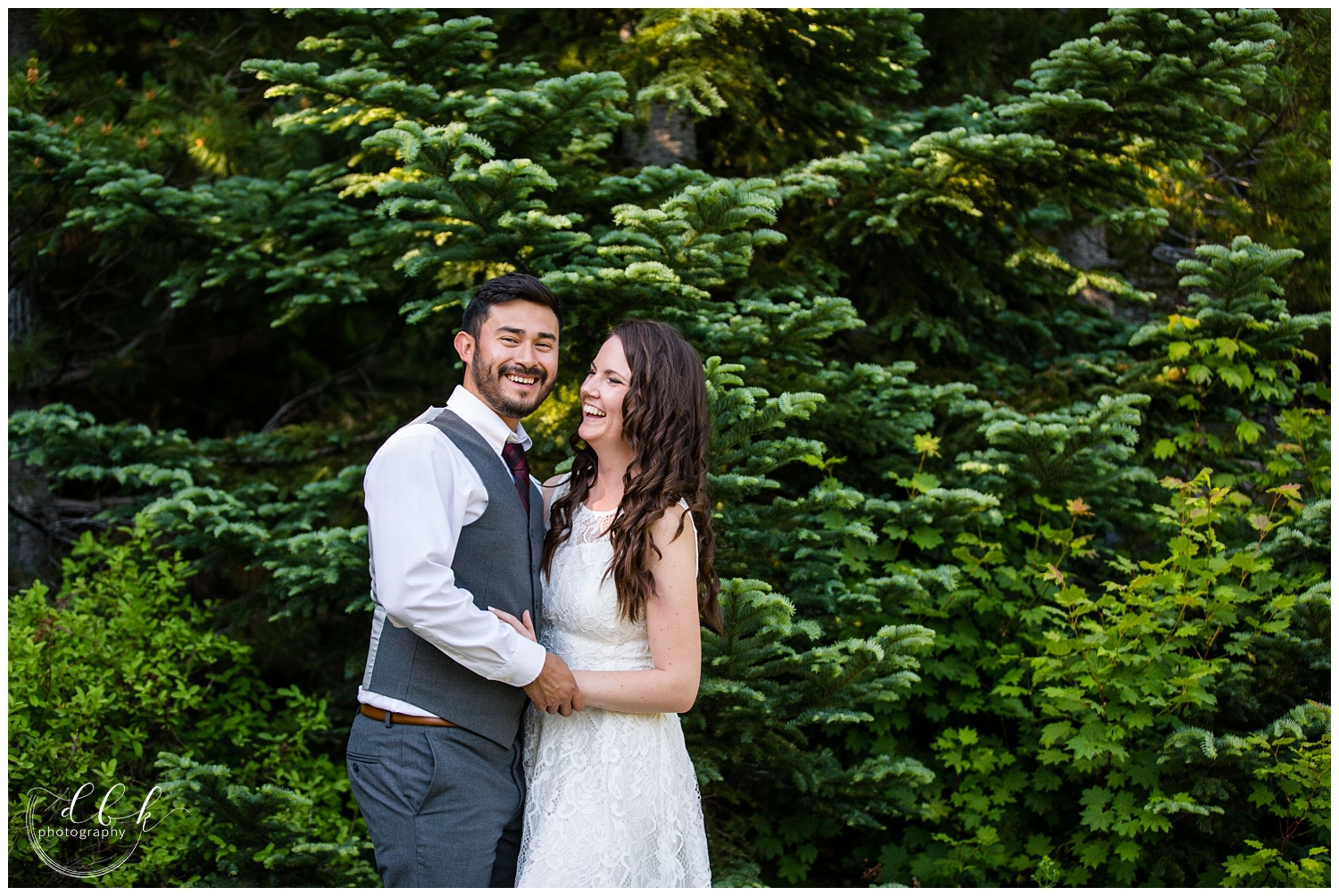wedding couple laughing together among evergreen trees in Snoqualmie Forest at Gold Creek Pond