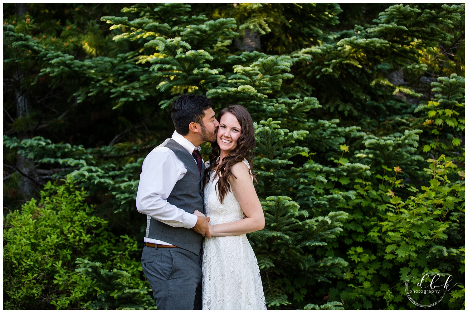 groom kissing his bride on the head for Gold Creek Pond summer engagement pictures