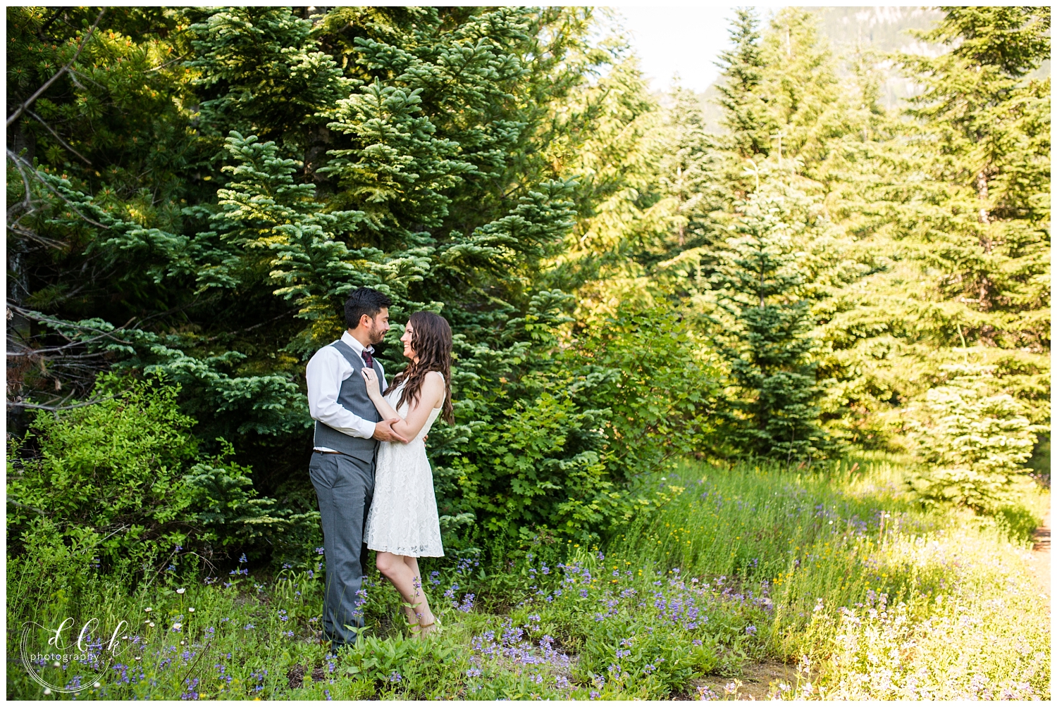 couple standing in brightly lit forest at Gold Creek Pond for engagement pictures