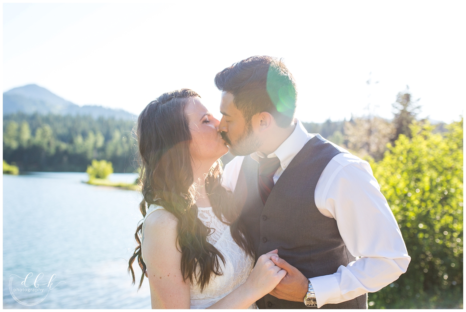 wedding couple kissing in the sunshine on the water at Gold Creek Pond during summer engagement pictures