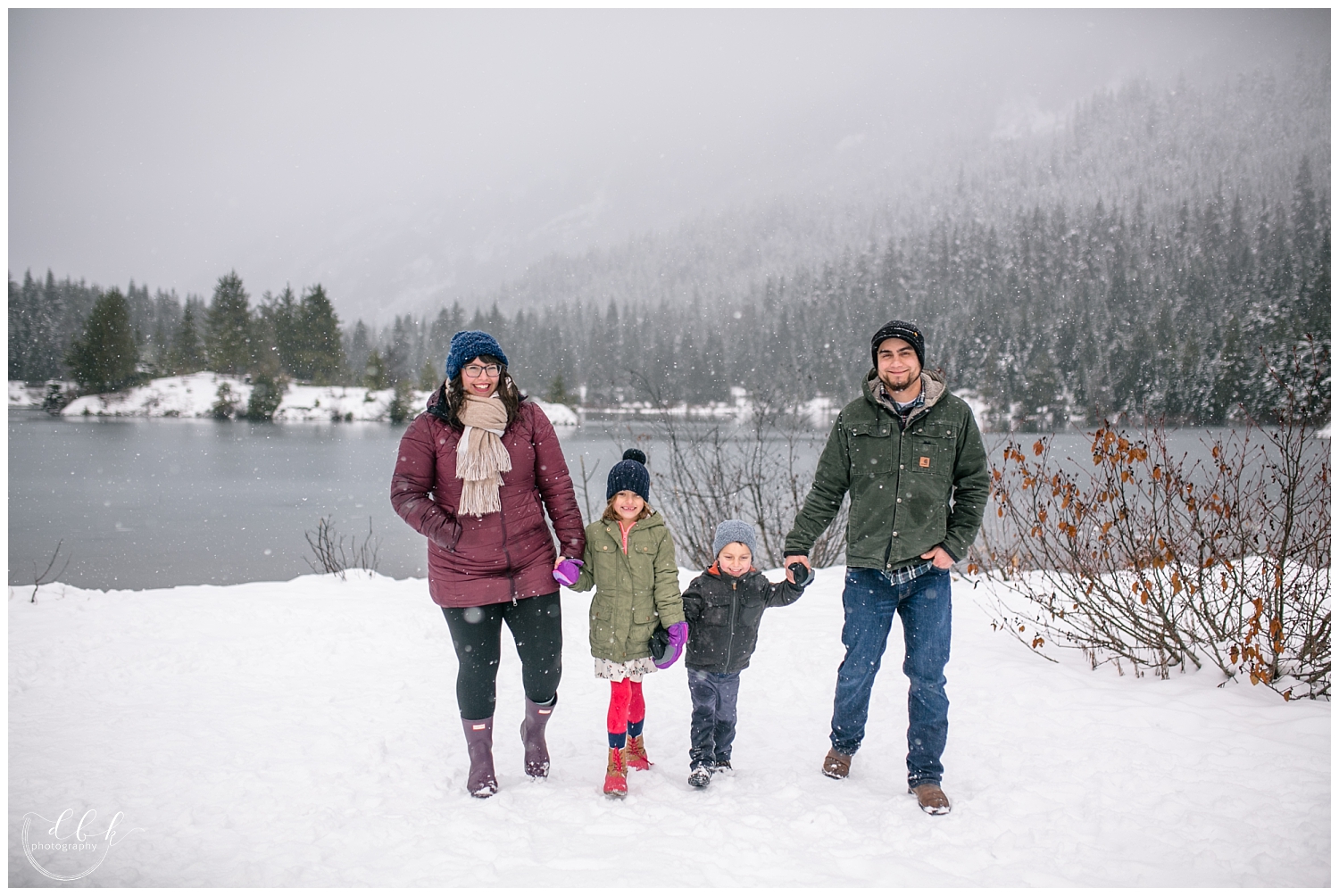 family of four walking toward the camera in the snow at Gold Creek Pond family portrait session