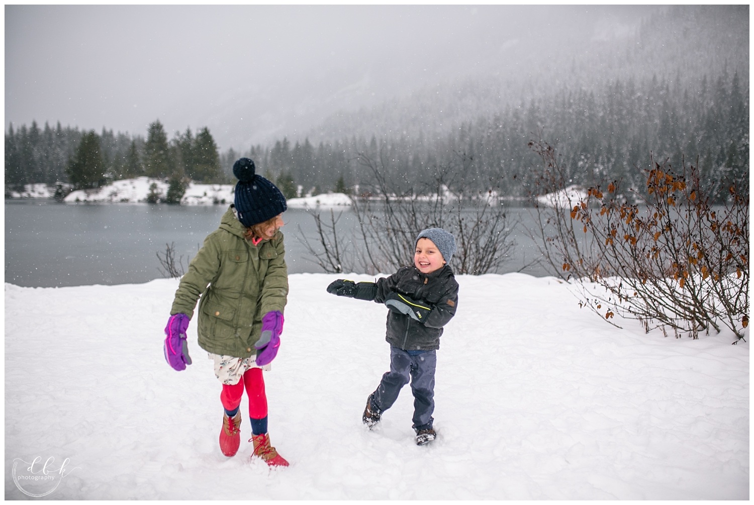 two kids playing together in the snow at Gold Creek Pond family portrait session