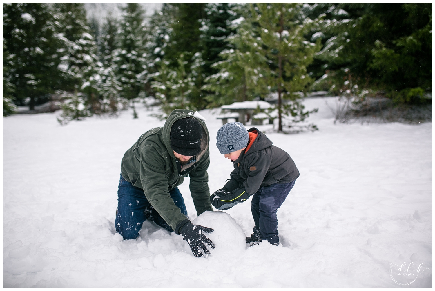 father and son making a snowman at Gold Creek Pond in Washington
