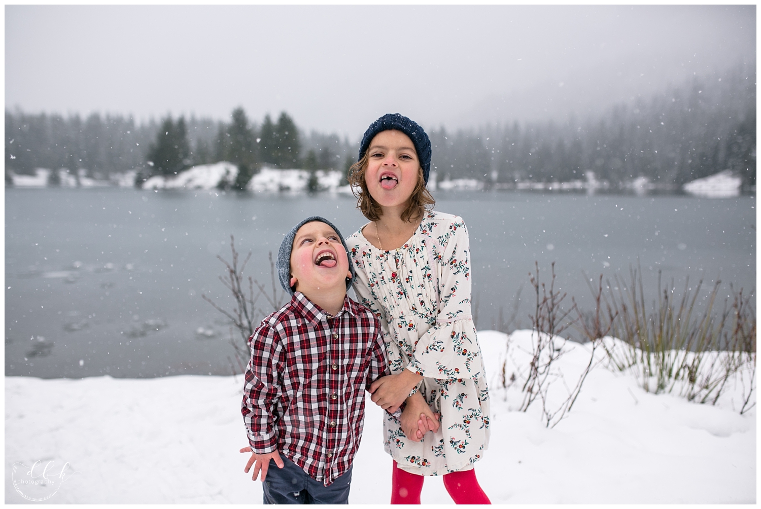 two kids catching snowflakes on their tongues during family portraits at Gold Creek Pond, Washington