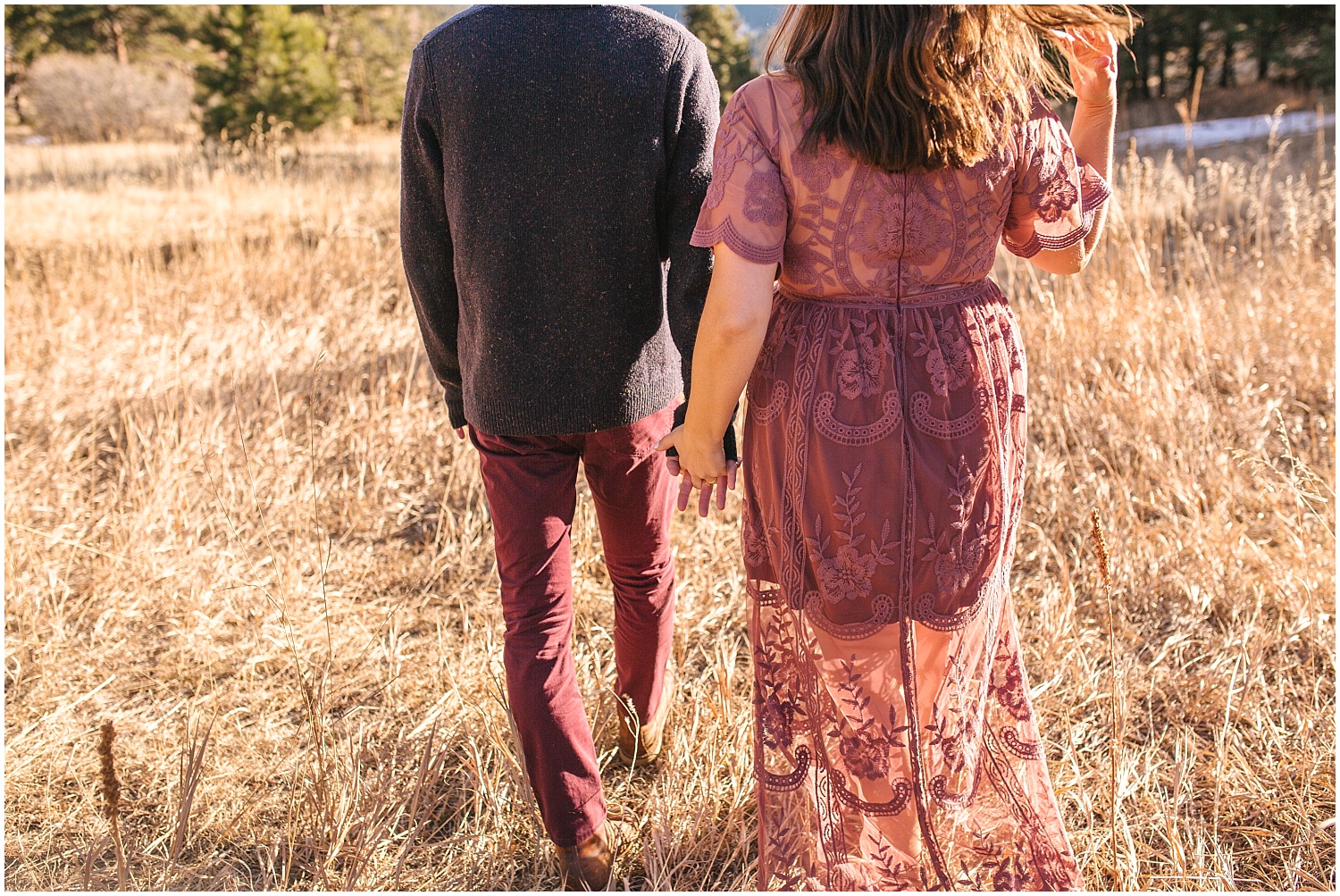 Couple walking in a tall grassy field for Mount Falcon engagement photos.