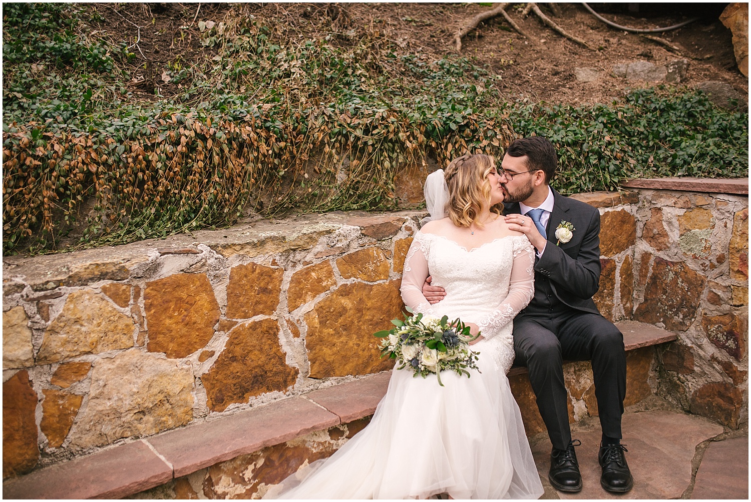 Bride and groom cuddling on a stone bench at Wedgewood Weddings Boulder Creek