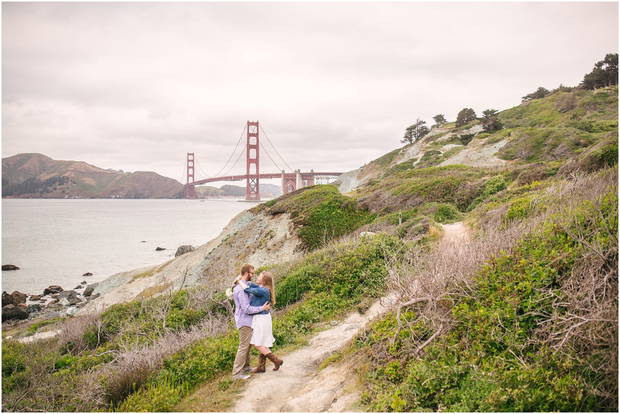 Couple standing in front of Golden Gate Bridge for Marshall Beach San Francisco engagement pictures