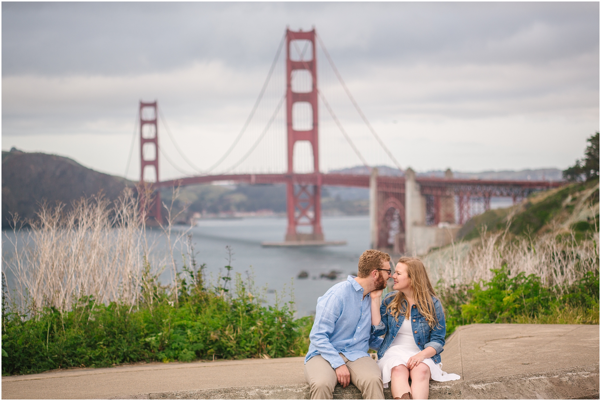 Engaged couple sitting at the Batteries in front of Golden Gate Bridge San Francisco