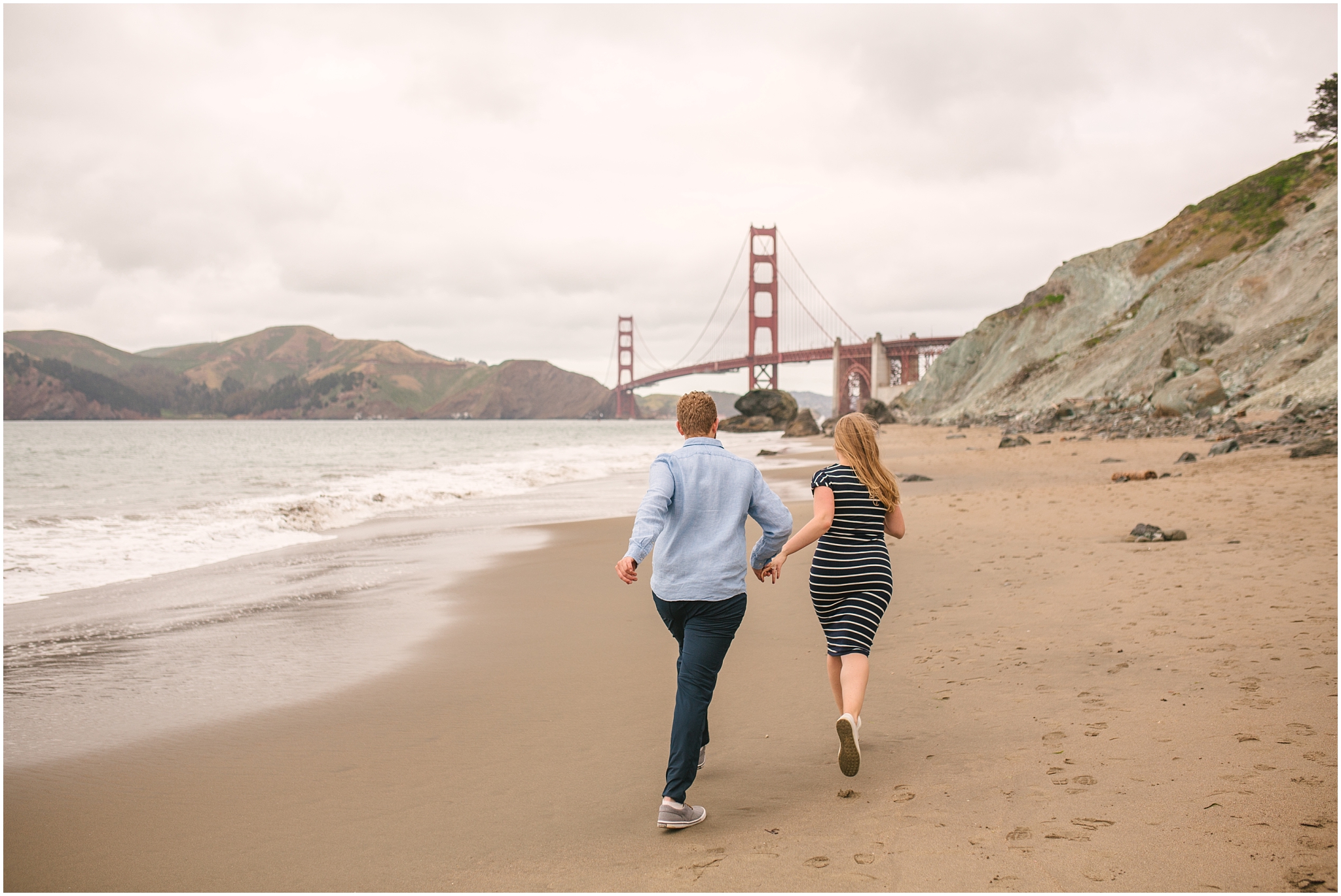 Couple running toward Golden Gate Bridge on the beach - Marshall Beach San Francisco engagement pictures