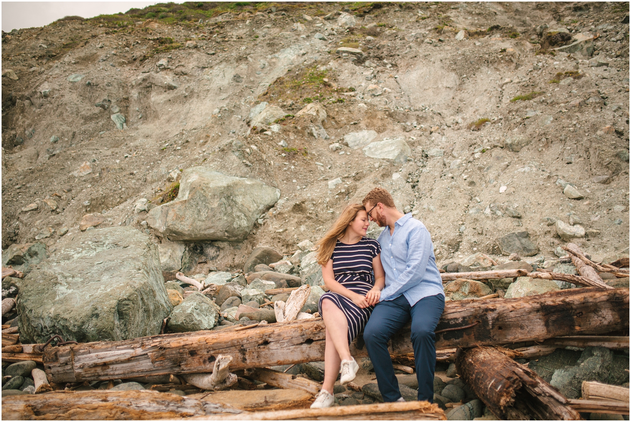 Couple sitting on driftwood for Marshall Beach San Francisco engagement pictures