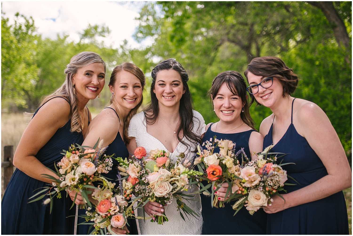 Bridesmaids in blue dresses with coral-colored desert bouquets by Floriography Flowers at Hyatt Regency Tamaya wedding in New Mexico