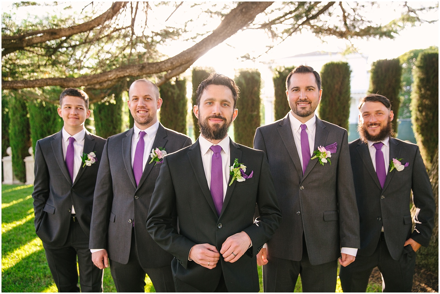 Groom and groomsmen dress in black suits with purple ties at Jefferson Street Mansion wedding