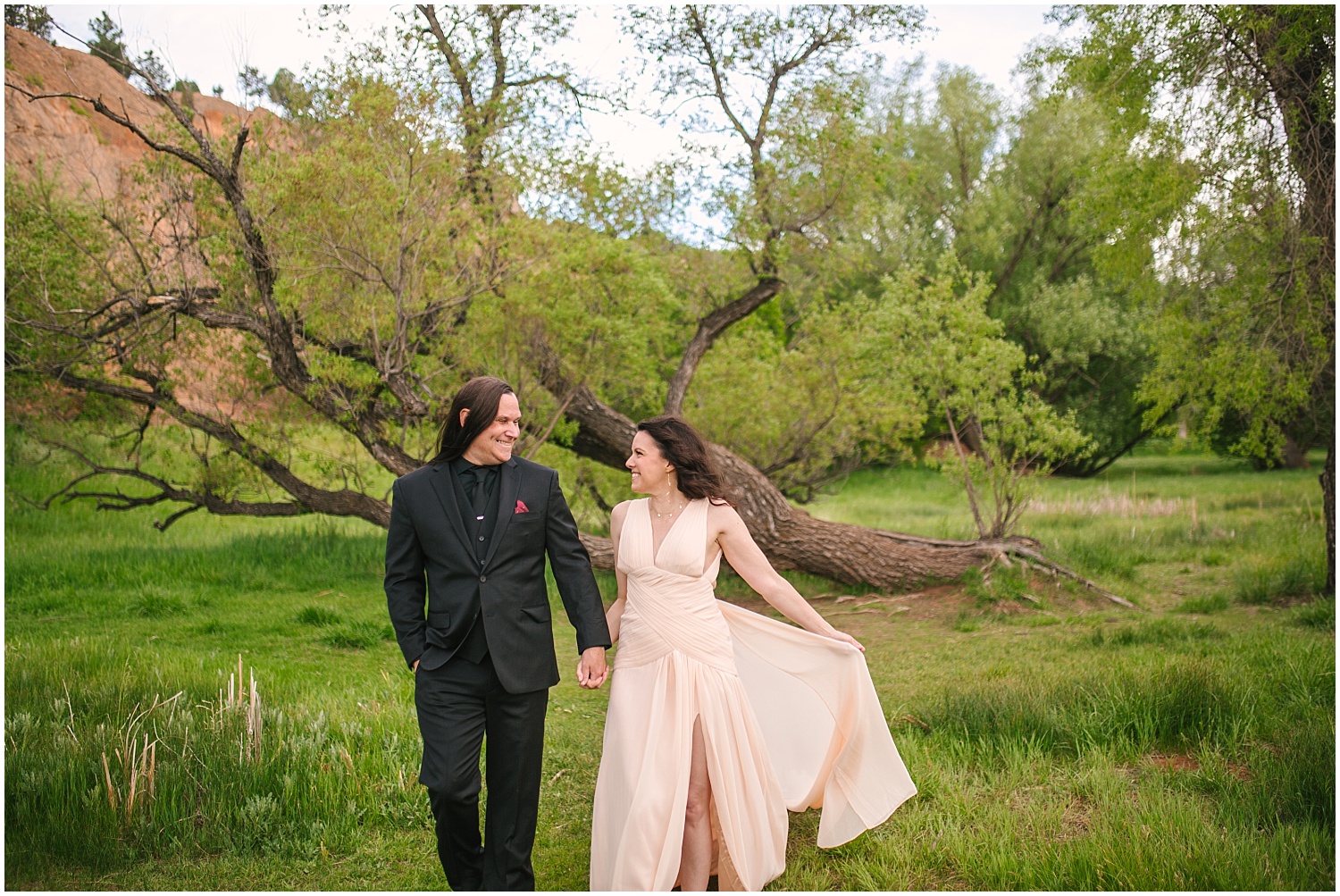 Couple walking in the green grass for Red Rock Canyon Open Space engagement photos in Colorado Springs