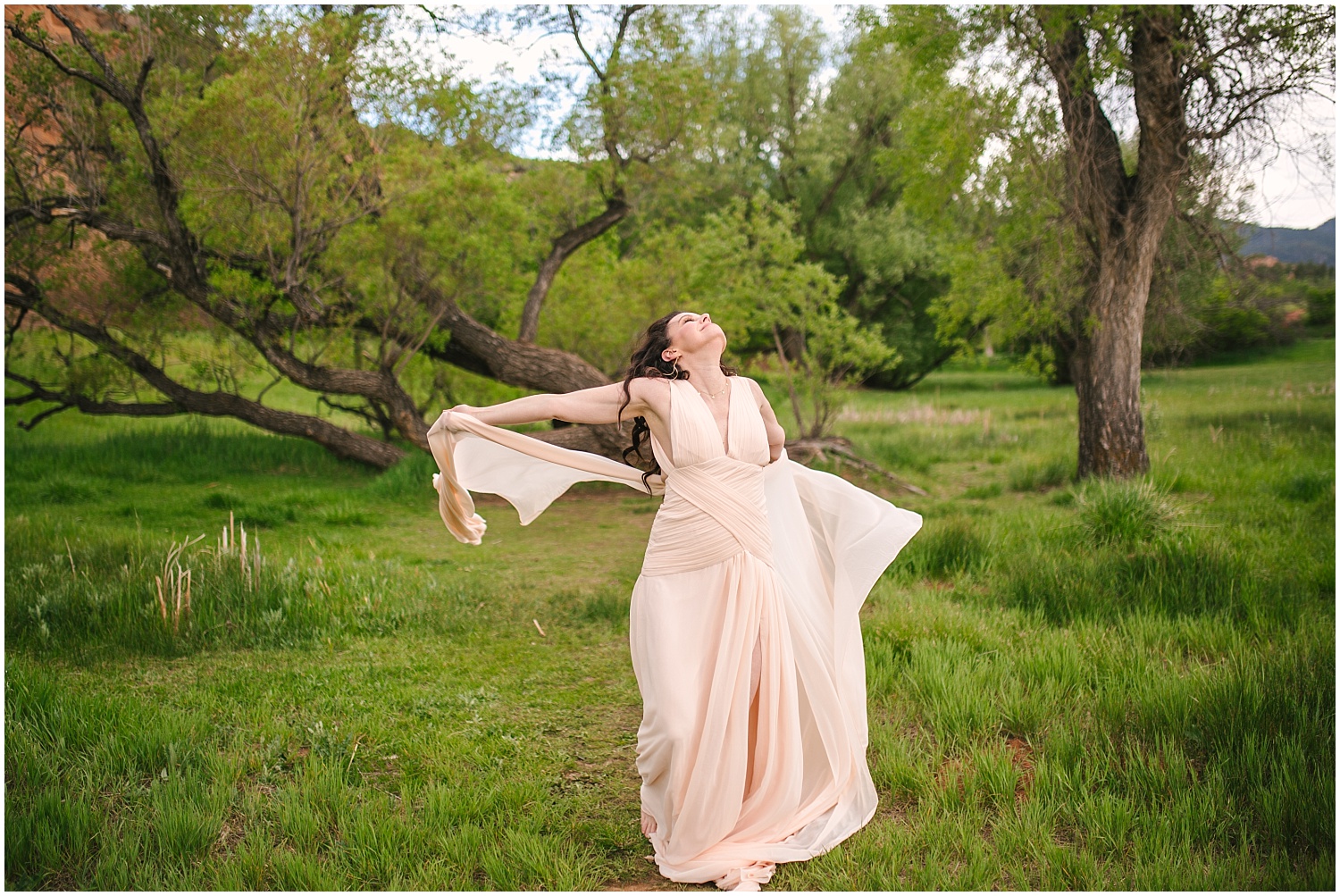 Bride dancing in flowing pink dress under large tree at Red Rock Canyon Open Space 