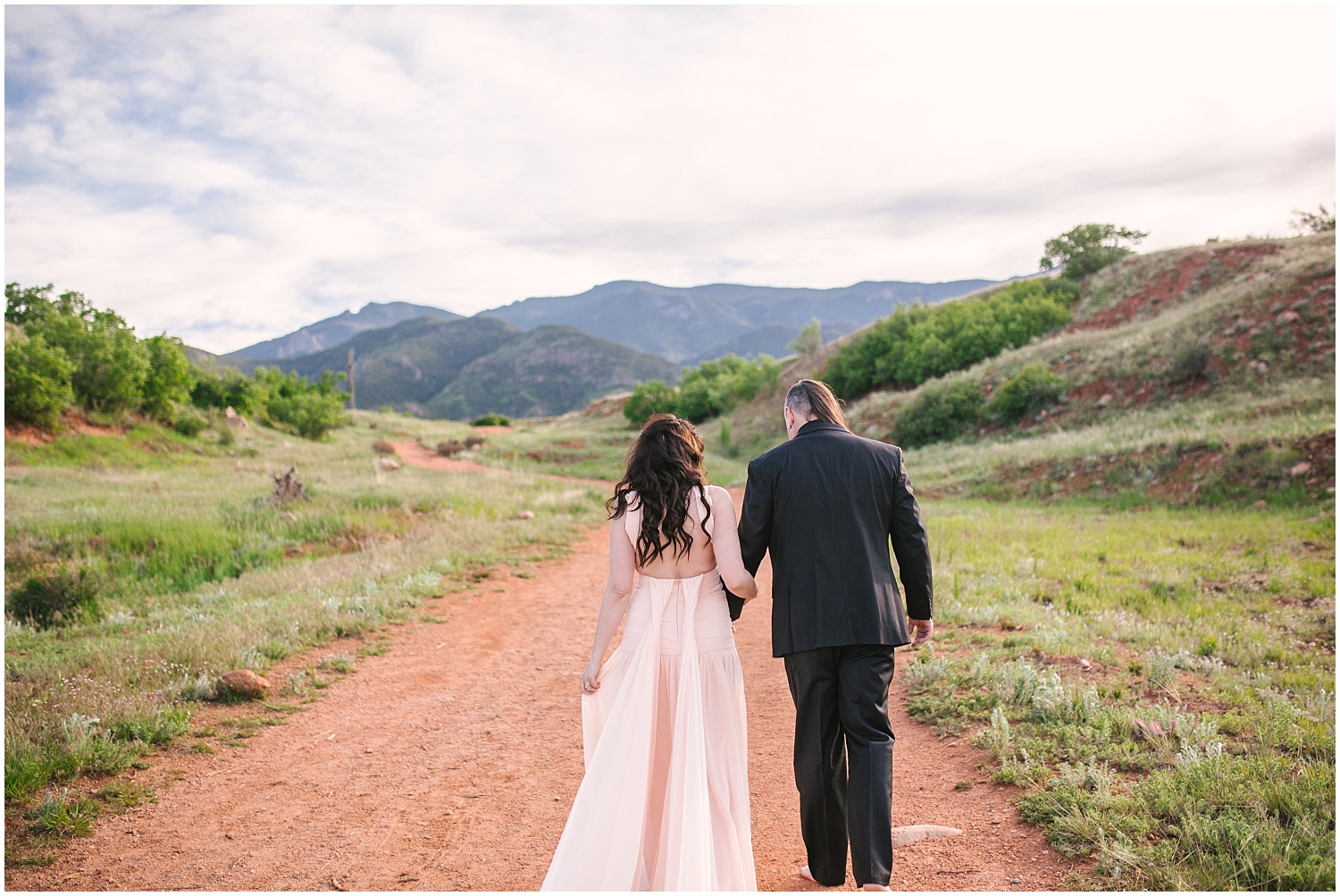 Bride and groom walking along dirt path at Red Rock Canyon Open Space for Colorado Springs engagement photos