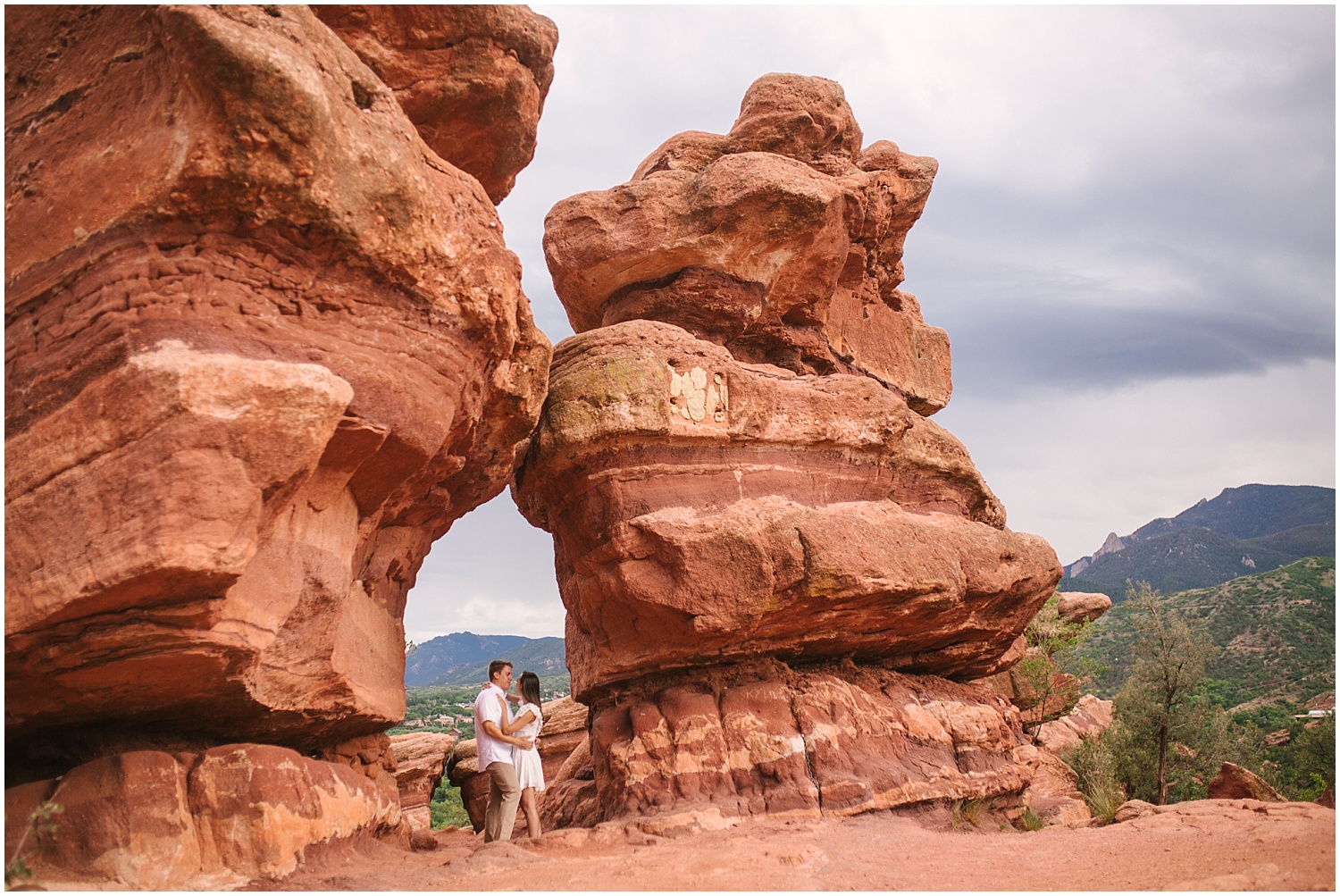 Engaged couple standing near giant red rocks at Garden of the Gods