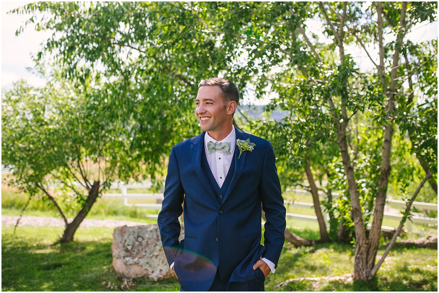 Groom in navy suit with light green bow tie and succulent boutonniere at Crooked Willow Farms