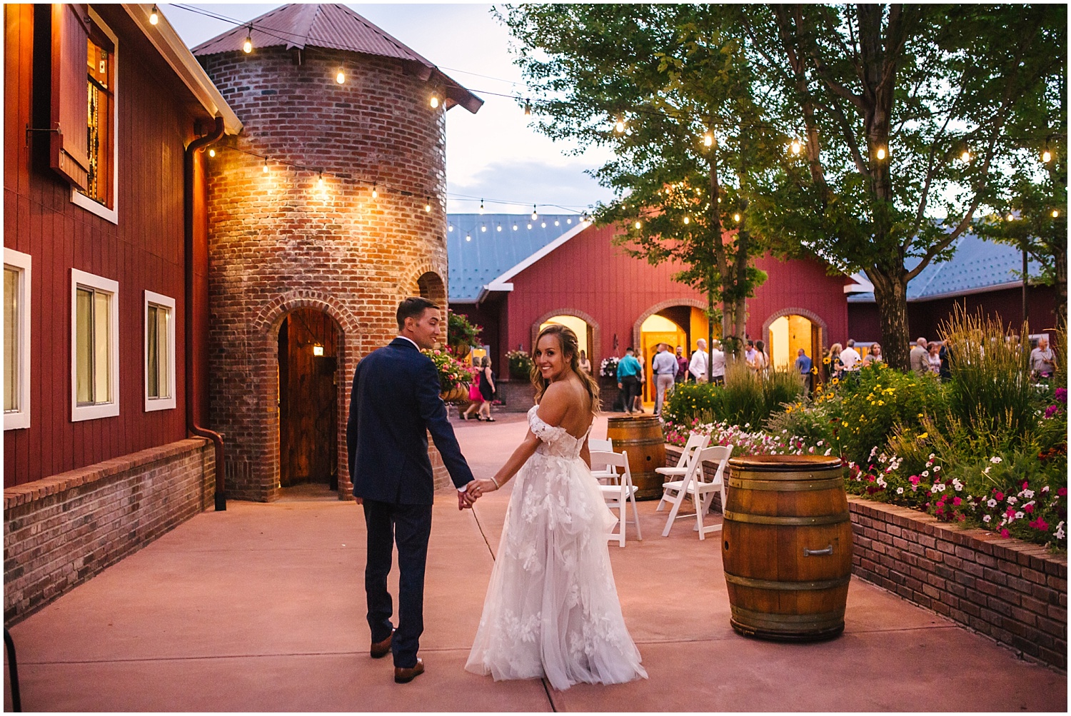 Bride and groom walk under the twinkle lights outside their Crooked Willow Farms wedding reception