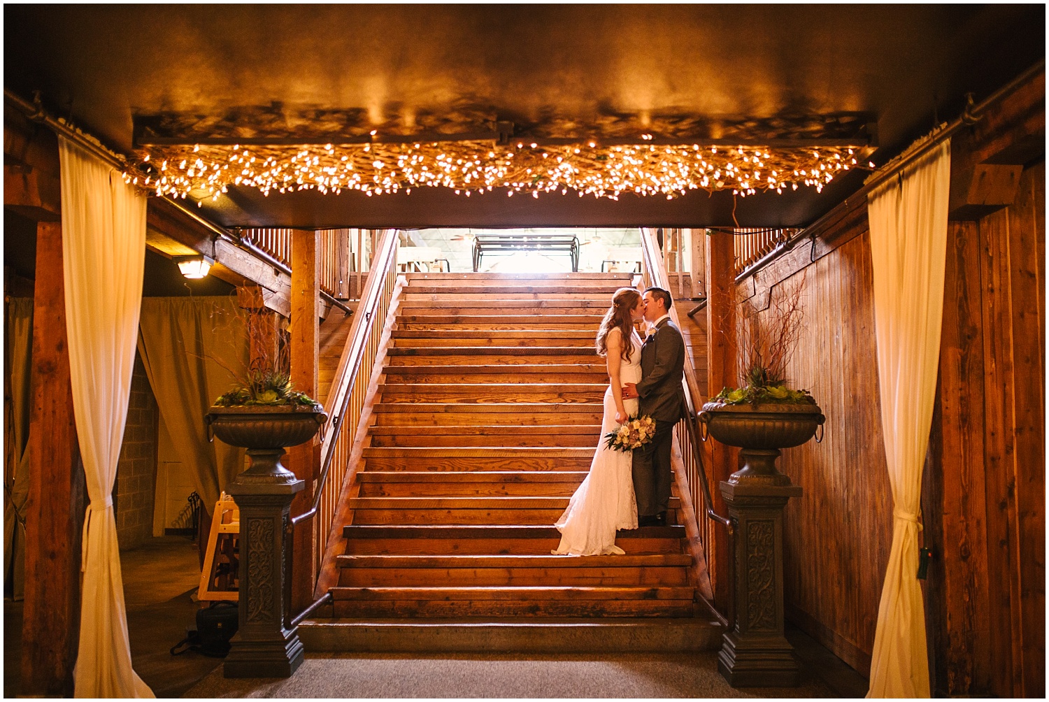 Bride and groom kissing on the stairs under twinkle lights at Lord Hill Farms