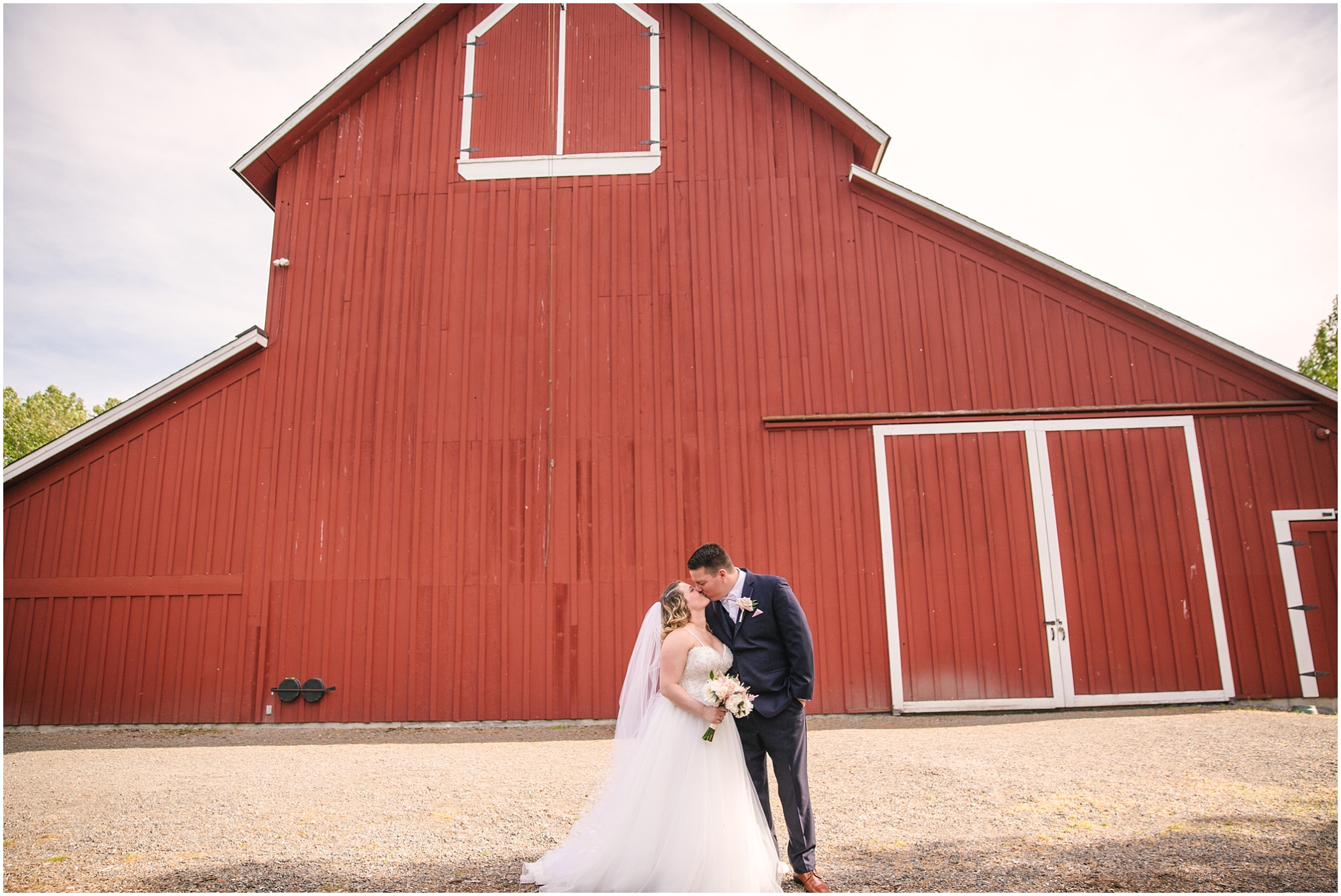 Bride and groom kissing in front of red Pickering Barn in Issaquah Washington