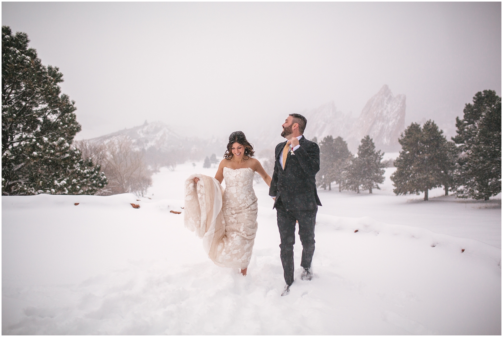 Bride and groom running through the snow together at winter wedding at Arrowhead Golf Club