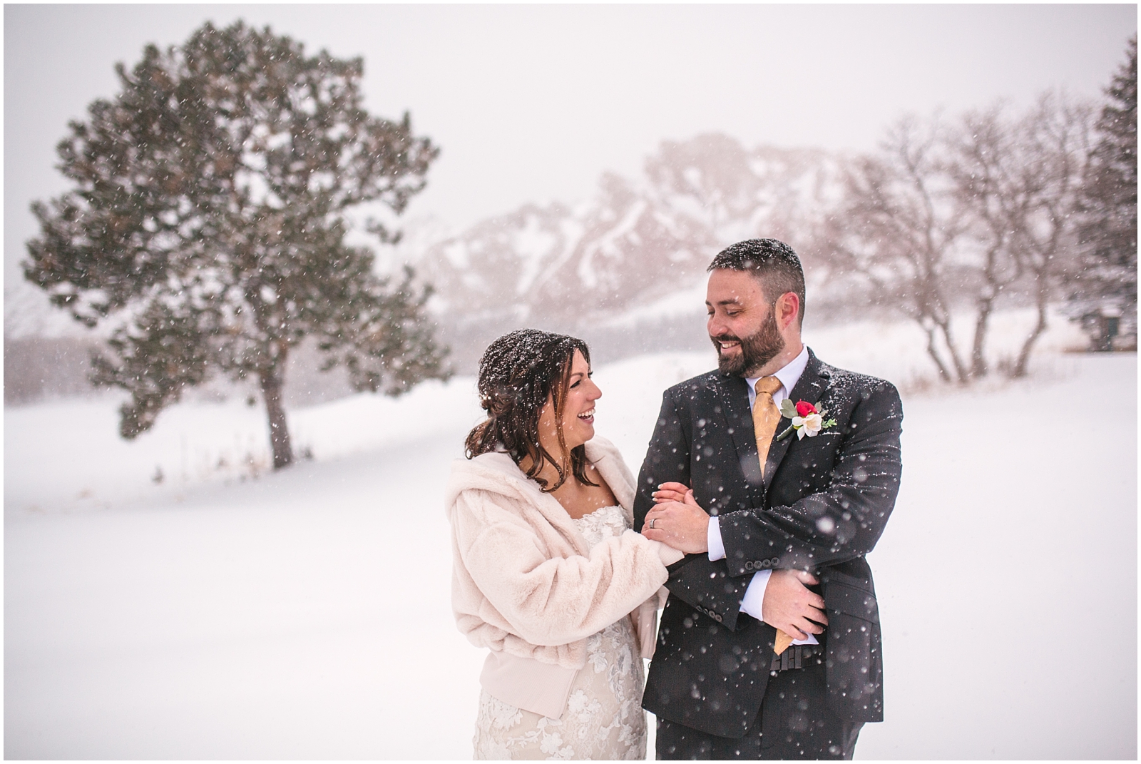Bride and groom laughing in the snow at Arrowhead Golf Club winter wedding
